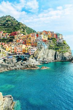 an island with many colorful buildings on it's side and blue water in the foreground