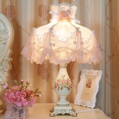 a white lamp sitting on top of a table next to a vase with flowers in it