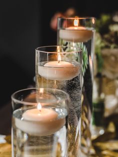 three candles are sitting in glass vases on a table