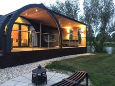 a house that is sitting in the grass next to a body of water with lights on