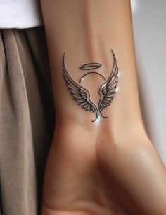 a woman's arm with an angel wing tattoo on the left side of her wrist