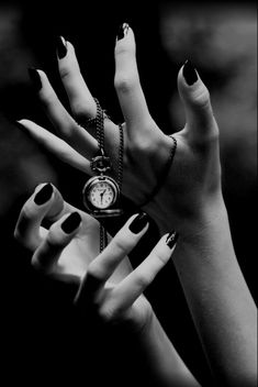 woman's hands with black and white manicures holding an antique pocket watch