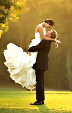 a bride and groom are dancing on the golf course in their wedding attire with trees in the background