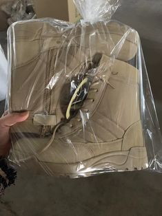 someone is holding up a pair of shoes in a plastic bag that they are packing