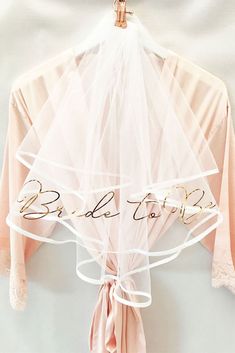 a bridal robe hanging on a hanger with the word bride to be written on it