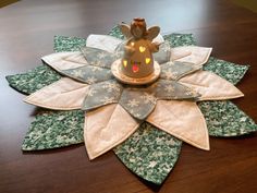 a table topped with a flower shaped object on top of a wooden table covered in green and white fabric