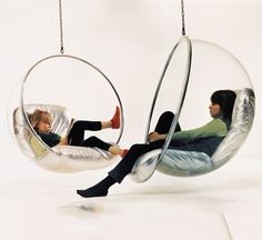 two people sitting in hanging chairs with their feet up