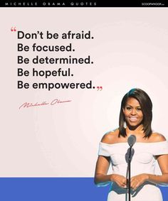 a woman standing in front of a microphone with a quote on the wall behind her