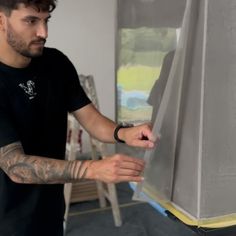 a man with tattoos on his arm is looking at an easel