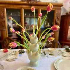 a vase filled with pink and yellow flowers on top of a white cloth covered table