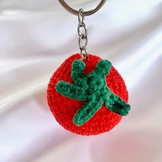 a crocheted keychain with a green and red flower on it's side