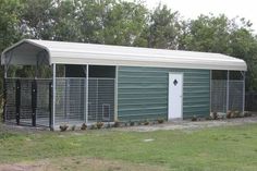 a green and white shed sitting in the middle of a field