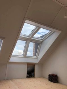 an empty room with two skylights in it's center and a wooden floor