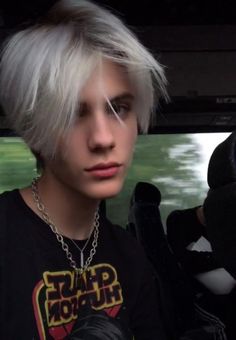 a young man with white hair wearing a black shirt and silver chain around his neck