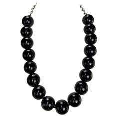 Presenting a beautiful black beaded Gianni Versace necklace, designed by Gianni Versace. From the late 1980s, this necklace features a strand of large black beads and is complete with a silver-tone chain closure. From the early days of Gianni's namesake brand, this classic necklace is the perfect addition to any wardrobe. Approximate measurements: Total length: 27" Diameter beads: 1" Formal Black Jewelry With Large Beads, Formal Black Necklace With Large Beads, Black Single Strand Beaded Necklaces For Party, Black Single Strand Beaded Necklace For Party, Party Black Single Strand Beaded Necklace, Black Beaded Necklace For Formal Costume Jewelry, Formal Black Beaded Costume Jewelry Necklace, Formal Black Beaded Costume Necklace, Black Beaded Costume Jewelry Necklace For Formal Occasions