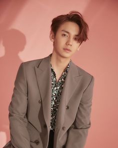 a young man in a suit and tie posing for a photo against a pink background