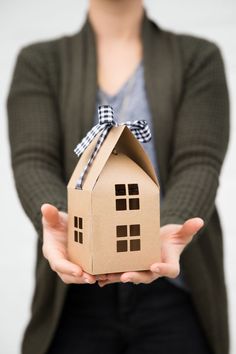 a person holding a cardboard house with a bow on it