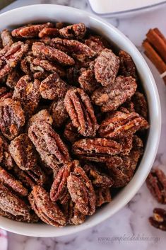 a white bowl filled with pecans and cinnamon sticks next to some other food items