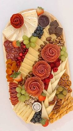 a platter filled with lots of different types of cheeses and fruit on top of each other