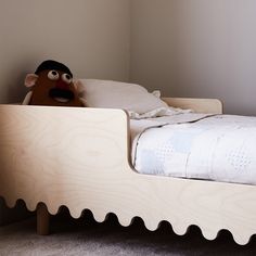 a stuffed animal sitting on top of a wooden bed