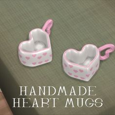 two heart shaped containers sitting on top of a green surface with the words handmade heart mugs