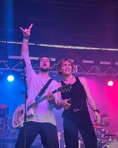 two young men on stage with one holding up his hand and the other pointing at something