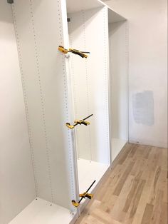 there are three white shelves with yellow handles on each shelf in the room and one is empty