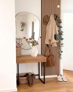 there is a coat rack and mirror in this room with shoes on the floor next to it