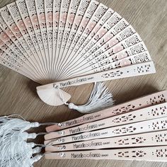 four wooden fans with tassels on top of a wood table next to each other