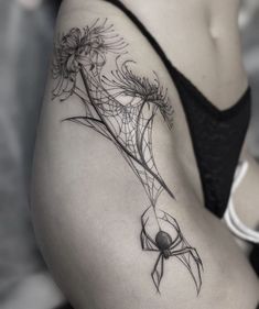 a woman's thigh with a spider and flowers tattoo on her lower back side