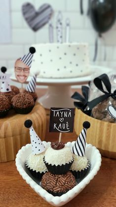 some cupcakes are in a heart shaped bowl on a table with other decorations