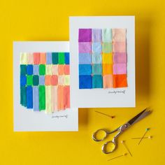 two cards with different colored squares on them next to scissors and thread spools