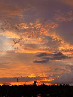 the sun is setting behind some clouds in the sky above water and trees on the shore