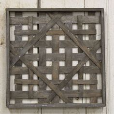 a square wooden basket hanging on the side of a white wall with wood planks