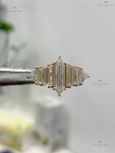 a diamond ring sitting on top of a piece of metal with a plant in the background