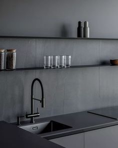 a kitchen with black counter tops and stainless steel sink faucet, open shelving above the sink