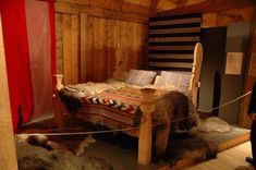 a bed in a room with sheep rugs on the floor and wood paneled walls