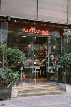 the entrance to azatar cafe with potted plants and chairs in front of it