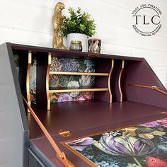 a purple desk with floral wallpaper and gold trimmings on the top shelf