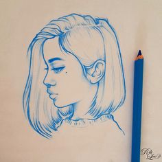 a blue pencil drawing of a woman's face on paper next to a pen