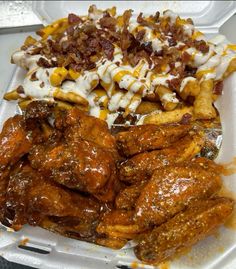 a plastic container filled with chicken wings, fries and coleslaw covered in sauce