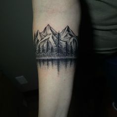 a man's arm with mountains and trees on it