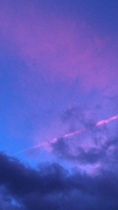 an airplane is flying in the sky at sunset or dawn with purple and blue clouds