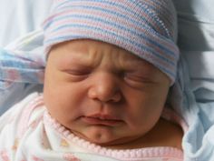 a newborn baby wearing a blue and white hat