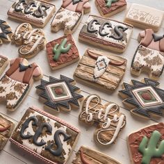 many decorated cookies on a table with cactus and cowboy theme decorations in the shape of horseshoes