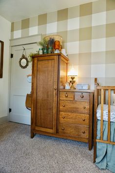 a baby's crib and dresser in a room with checkered wallpaper