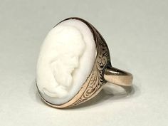 "Beautiful antique cameo ring from the early Victorian era in 10K yellow gold. This very special ring features a beautifully carved high relief cameo carved in white coral, mounted in a sturdy engraved Victorian era bezel mount . The top of the ring measures 19mm north to south. Solid gold bezel, back and ring shank. Ring size 5 1/2 and sizable. Please allow one week for sizing. One month layaway payment plans available on rings $500 and over. Approximate Age - Victorian Gemstone(s) - white coral cameo Metal - 10K Gold Weight - 5 grams Ring size - 5 1/2 Marks - illegible marks Makers Mark - illegible Comments -  Service & Sizing Information: If you require ring sizing or service, kindly follow the link below to add the appropriate service fee from the dropdown menu at the time of purchase. Antique Cameo Signet Ring For Weddings, Heirloom White Oval Engraved Ring, Heirloom White Engraved Oval Ring, Victorian Oval Carved Rings, Elegant Carved White Rings, Heirloom White Oval Signet Ring, White Oval Heirloom Signet Ring, Elegant White Carved Rings, Antique White Cameo Rings