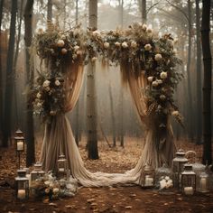 an outdoor wedding arch with flowers and candles in the woods on a foggy day