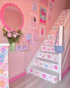 the stairs are decorated with pink flowers and pictures on the wall above them, along with a mirror