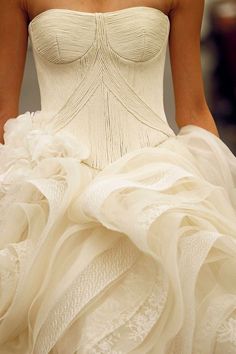 a woman in a white wedding dress walking down the runway